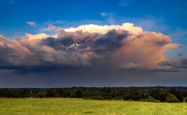 green field with big dark rain  cloud