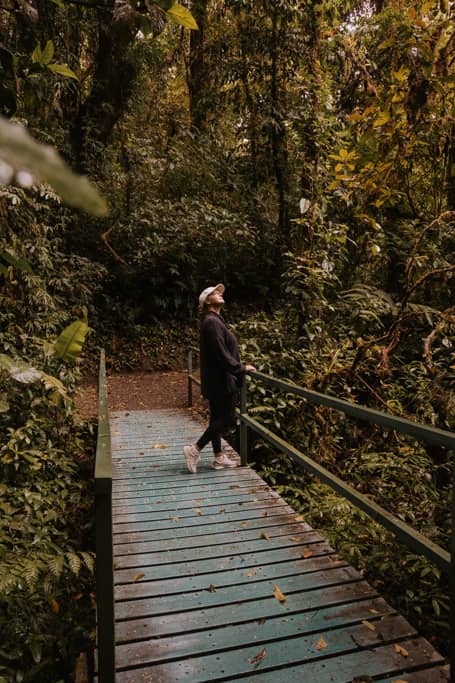 a woman standing on a blue bridge in the Monteverde Cloud Forest Biological Preserve