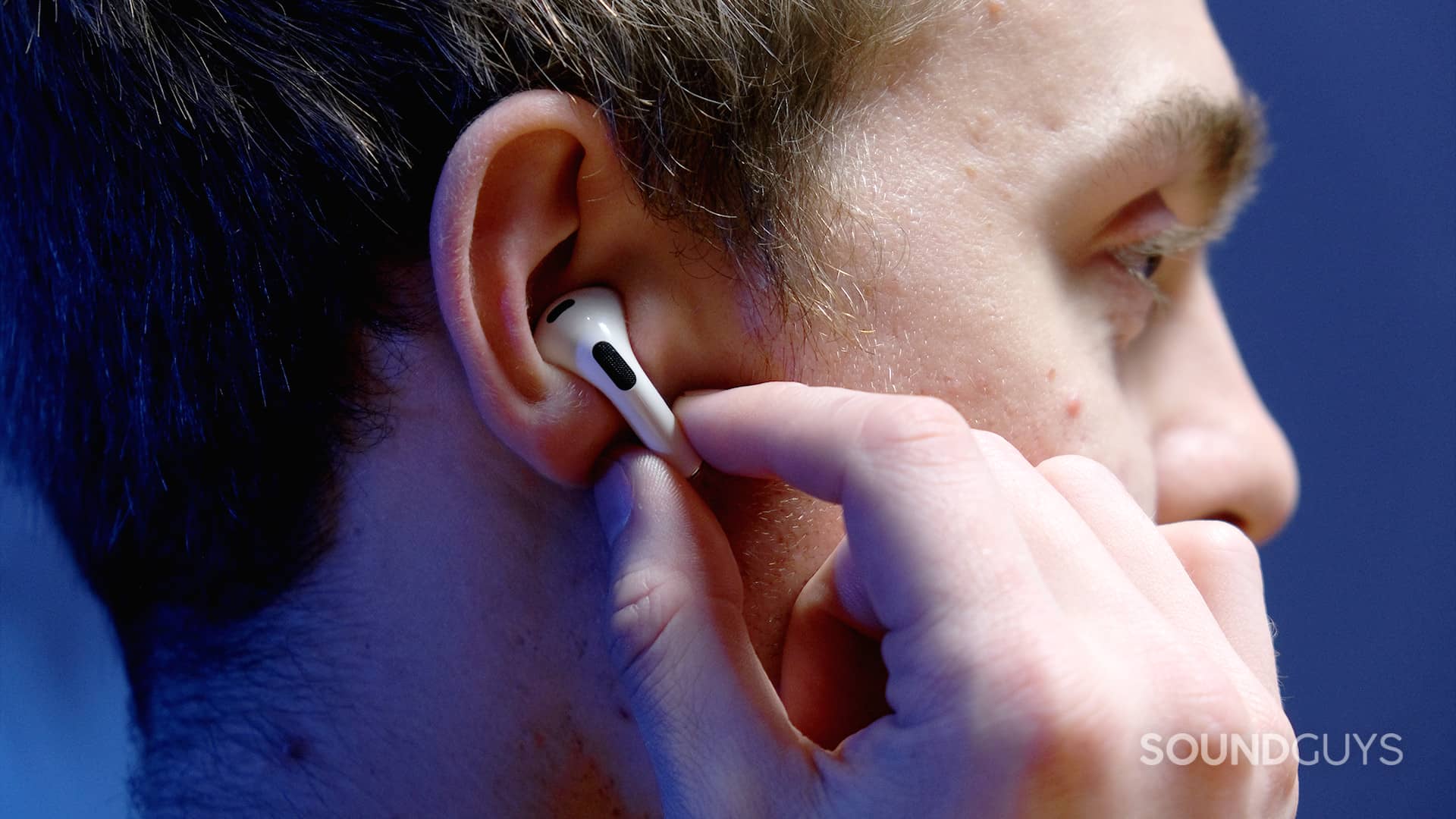 A hand holds the AirPods (3rd generation) in the right ear while touching the force sensor stem.