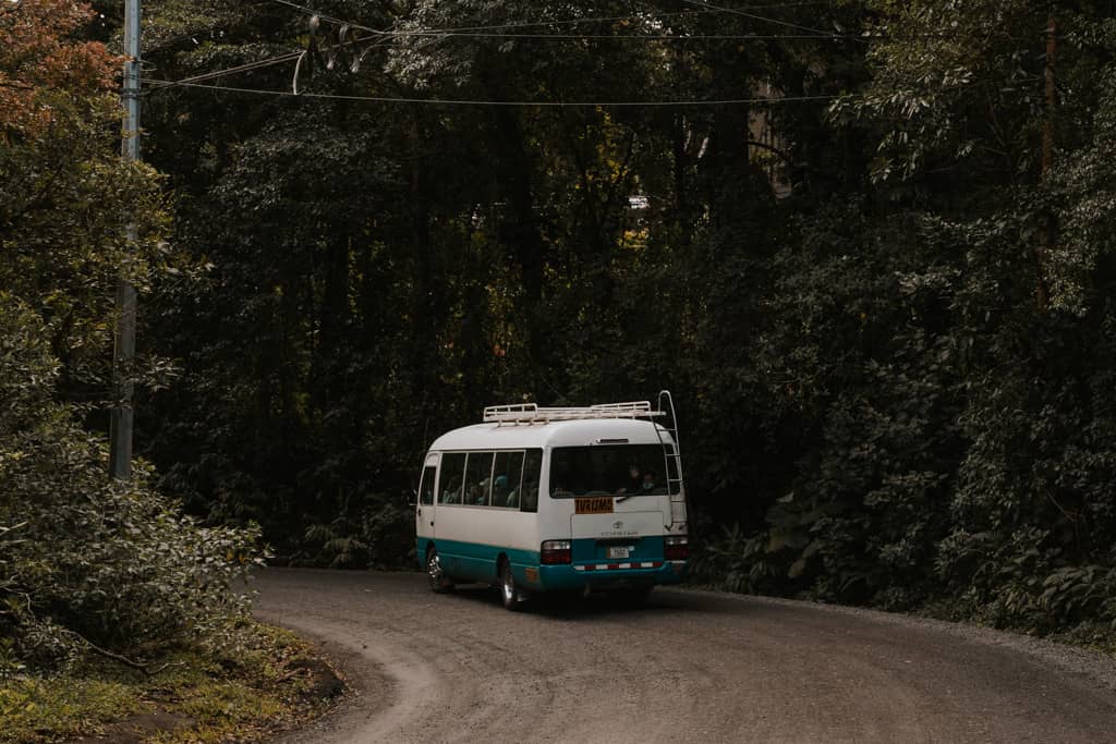 white and blue shuttle driving on road towards the Monteverde Cloud Forest Biological Preserve