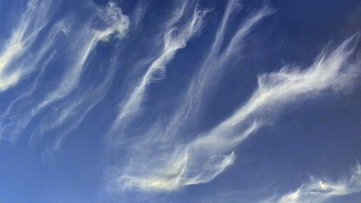 wispy white strings of  cloud on blue sky