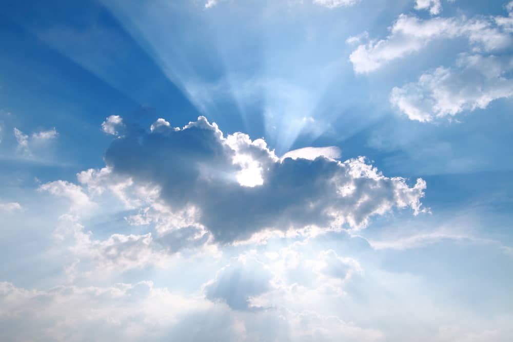 The sun is peeking behind a cumulus cloud in the sky in this image.