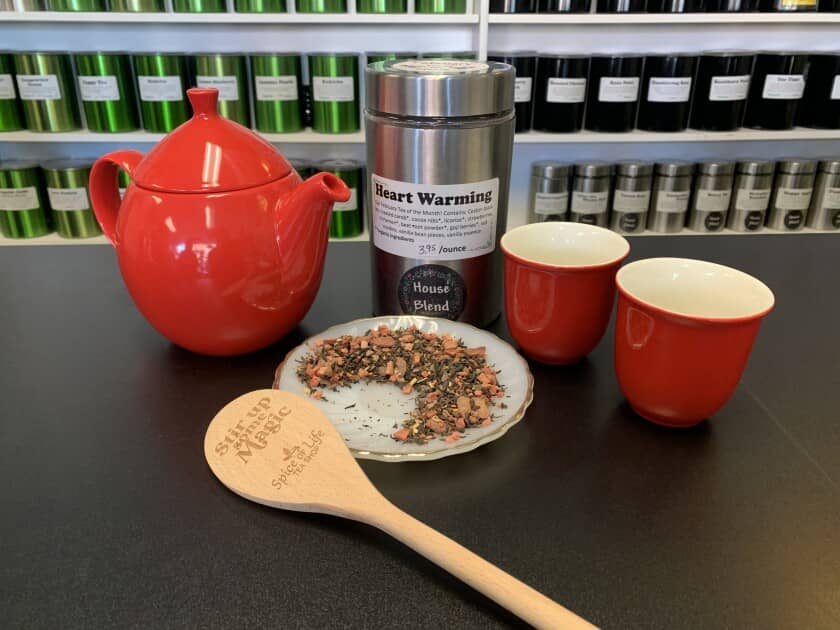 Loose tea, a tea kettle and mugs sit on a counter