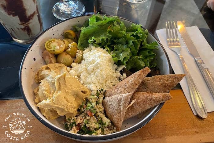 Large bowl with hummus, pita, olives, etc.