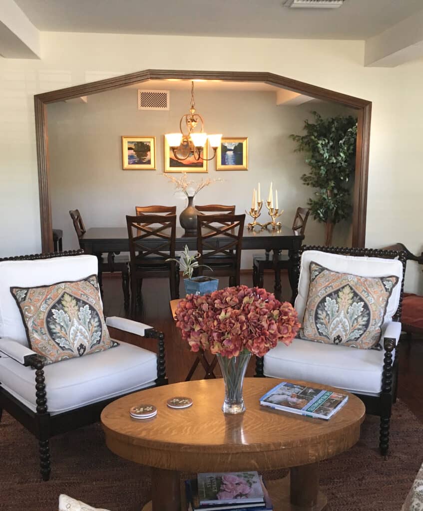 LIving room with arch to dining room, dark wood trim, floor and furniture. Benjamin Moore Spanish White cream off-white paint color on walls. Client photo of Kylie M Interiors