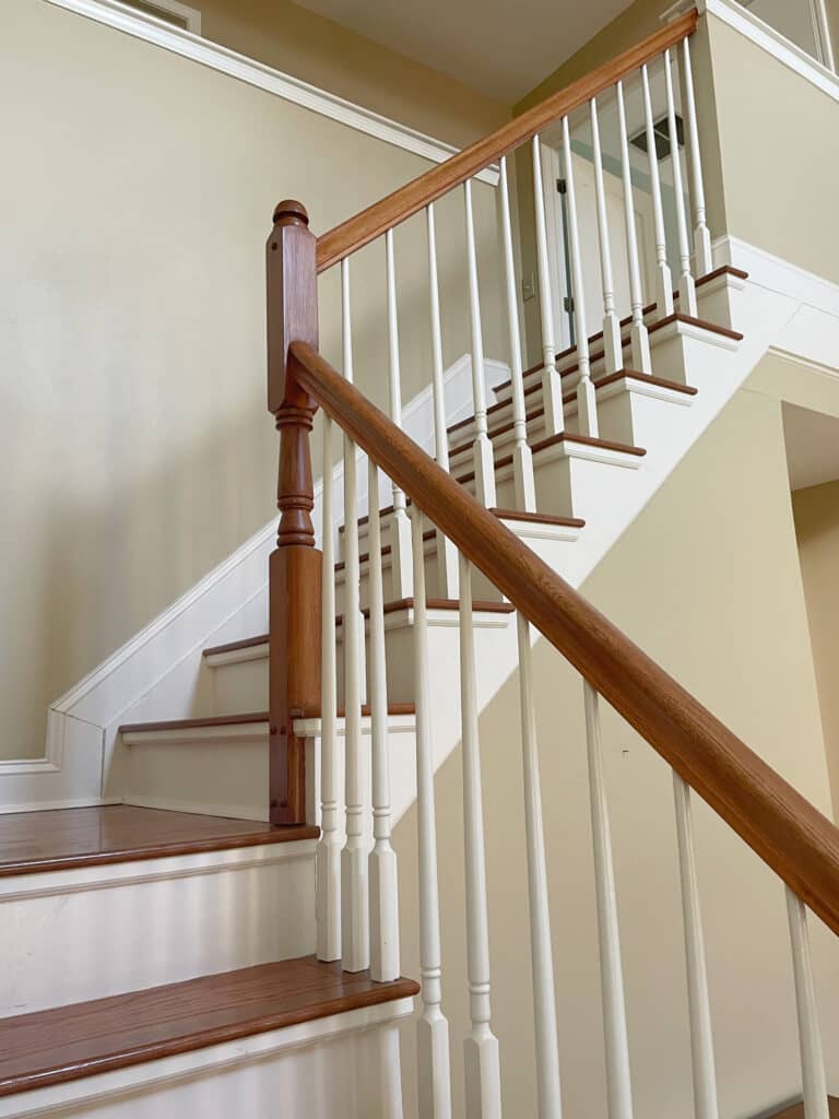 Benjamin Moore Linen White creamy trim and stairs with wood steps and hand railing, Sherwin Williams Whole Wheat beige tan on walls in staircase